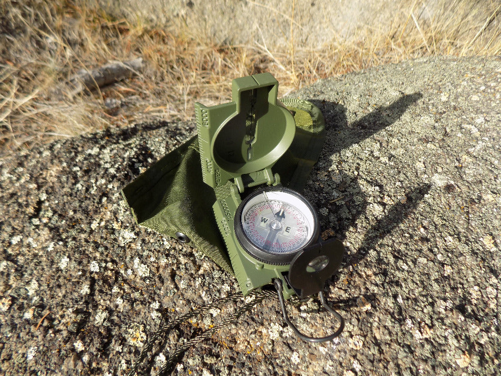 Commenga Lensatic Compass - compaas open on a rock - Wilderness Survival Systems : Picture