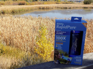 Survival - Intrepid Water Bottle in Packaging Next to pond - Wilderness Survival Systems : Picture 